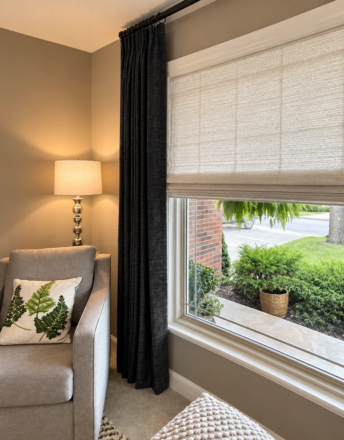 Layered drapery and a woven shade beside a comfortable reading chair